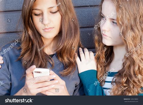 Teenage Girl Comforting Her Friend Reading Sad Message