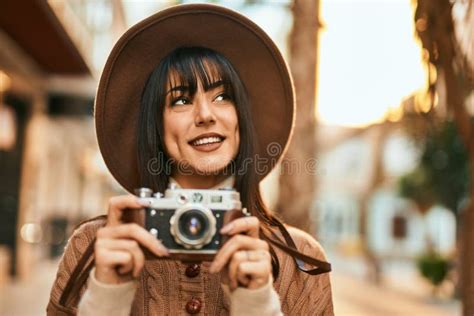 Brunette Woman Wearing Winter Hat Smiling Using Vintage Camera Outdoors
