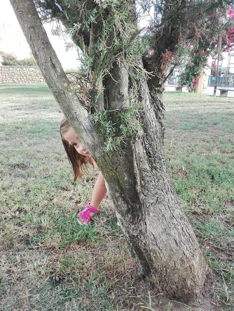 Premium Photo Cute Girl Hiding Behind Tree At Park
