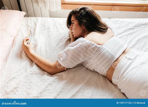 Portrait Of Young Sad Woman Lying On The Bed Looking Smartphone Feels