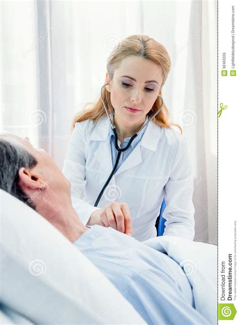 Middle Aged Patient Lying On Bed And Doctor Examining Him With