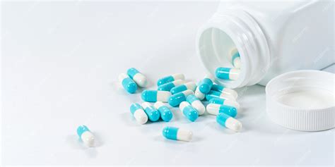 premium photo blue and white capsules pills pouring from the bottle on white background
