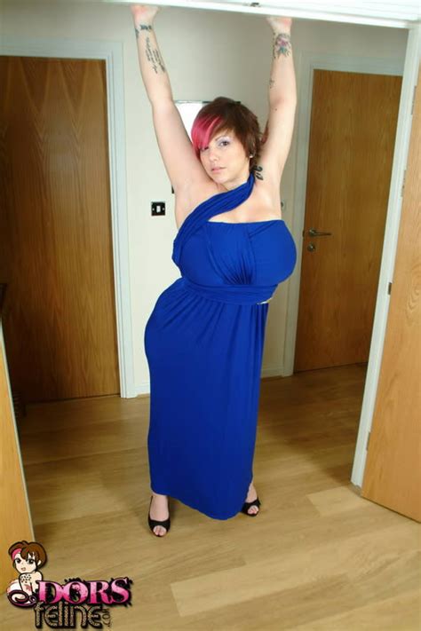 une jeune fille tatouée et perverse dans une robe bleue sexy montrant ses gros seins photos