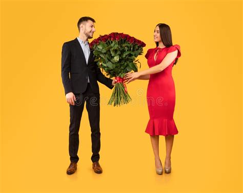 Man Giving T To Girlfriend Standing On Yellow Studio Background