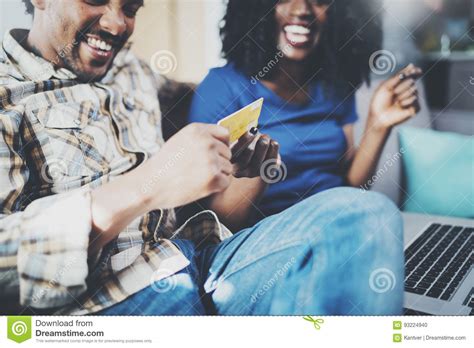 Happy Young African American Couple Sitting On Sofa At Home And