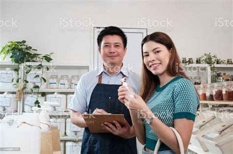 Portrait Of An Asian Male Shopkeeper And A Female Customer In A Refill
