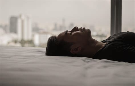 Asian Man Feels Sad Alone On Bed With City Background Stay Home