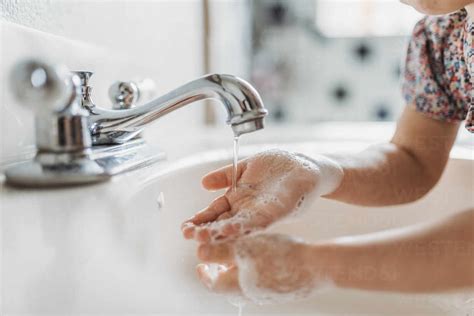 Close Up View Of Young Child Washing Hands With Soap In Sink Stock Photo