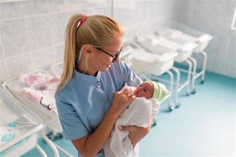 Premium Photo Young Nurse Standing In Maternity Ward And Holding