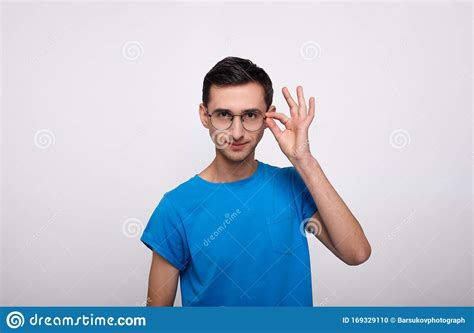 A Brooding Handsome Man Holds On To The Arc Of Glasses Stock Photo