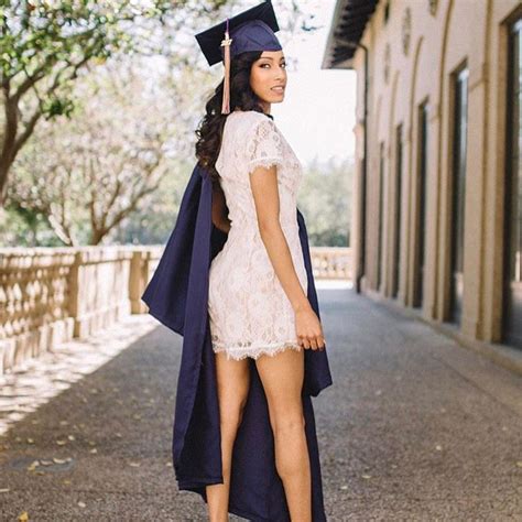 A Woman Wearing A Graduation Cap And Gown Is Standing On The Street
