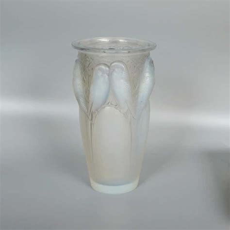 A Glass Vase With Two White Birds On The Bottom And One Is Sitting In Front Of It