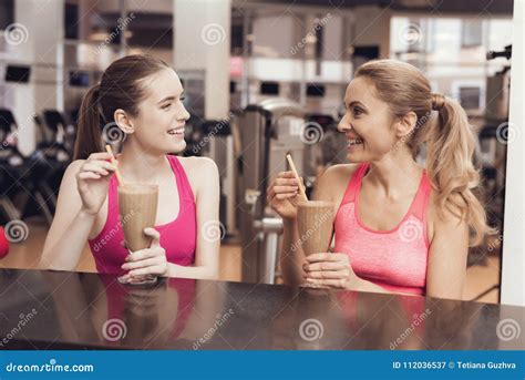 Mother And Daughter Drinking Protein Shakes At Gym They Look Happy Fashionable And Fit Stock