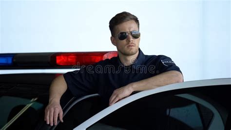 Serious Patrol Officer In Sunglasses Monitoring Road Standing Near Car