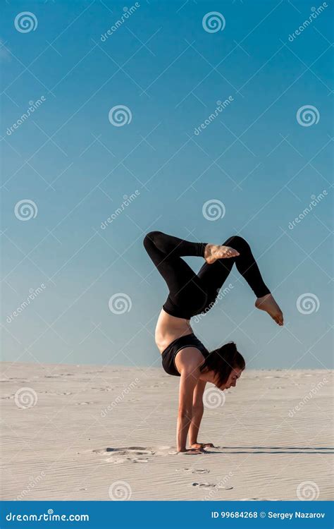 Young Woman Practicing Handstand On Beach With White Sand And Bright