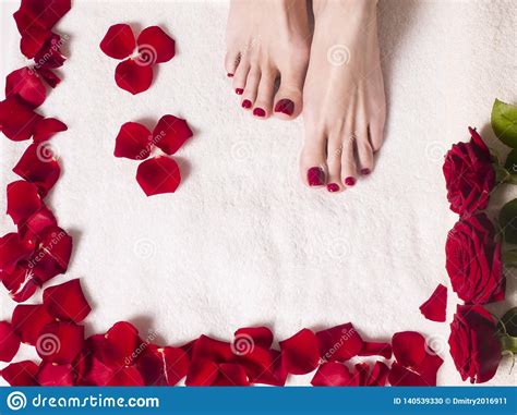 Beautiful Female Feet With A Red Pedicure In A Bath With Salt And Rose