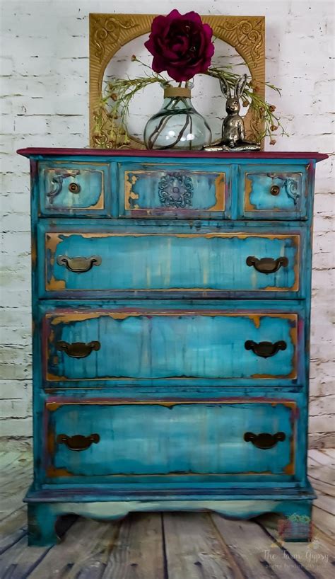 An Old Dresser Painted In Blue And Gold With A Rose On Top