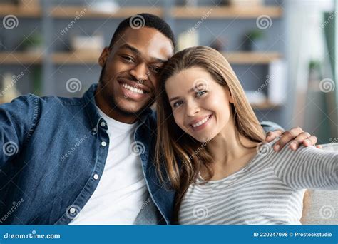 Portrait Of Cheerful Young Romantic Interracial Couple Taking Selfie Together At Home Stock