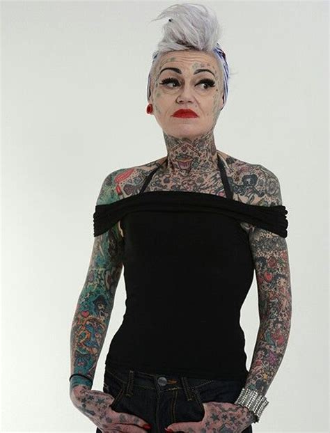 a woman with tattoos and piercings standing in front of a white background