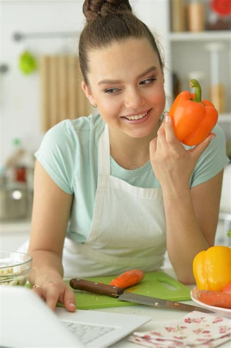 Portrait Of Beautiful Young Woman Making Salad In Kitchen Stock Photo