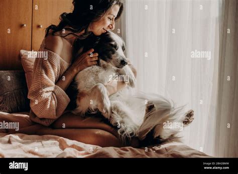 Glückliche Frau Die Zu Hause Auf Dem Bett Saß Und Ihren Hund Streichelte Stockfotografie Alamy