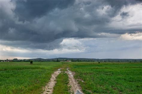 Dirt Road Through Green Fields And Storm Clouds On The Sky Stock Image