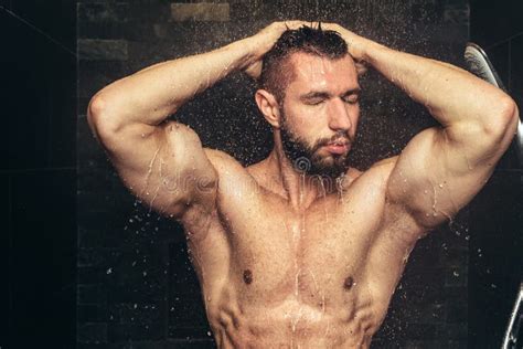 bodybuilder taking shower after training handsome man in shower with water drops and splashes
