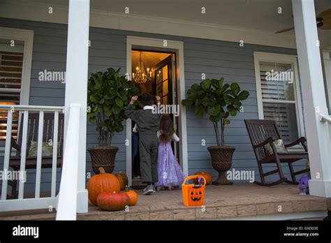 Brother And Sister Trick Or Treating At Neighbours Front Door Stock
