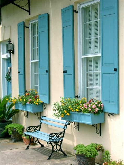 Glossy black vintage barn sconces are mounted to a white paneled home exterior on either side of a blue front door accented with a single glass panel, a brass. Fresh Summer Looks on Modern Shutters