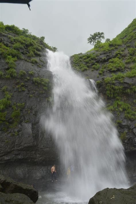 Vertical Shot Of People Standing Under Bhivpuri Waterfalls In Ashane