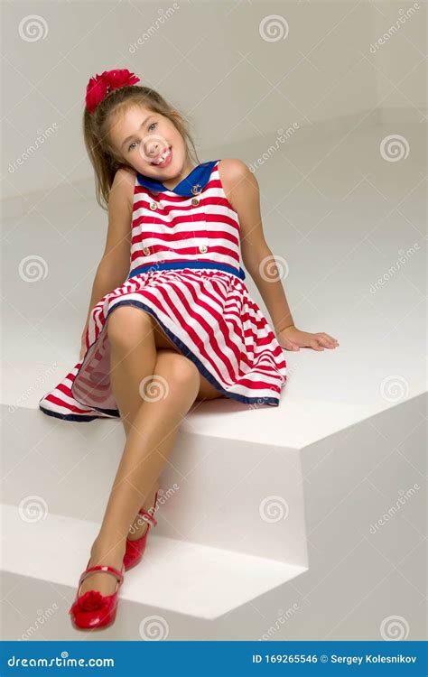 Beautiful Little Girl Is Sitting On The White Staircase Stock Photo