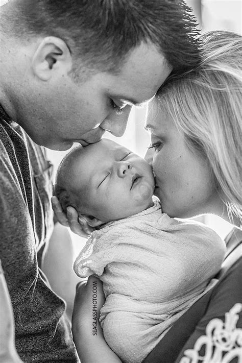 Close Up Black And White Photo Of Mom And Dad Kissing Their Newborn Son