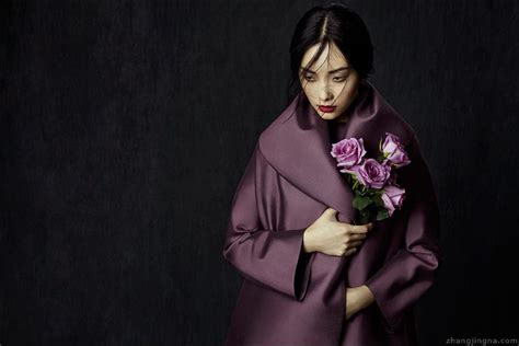 A Woman In A Purple Coat Holding A Bouquet Of Flowers