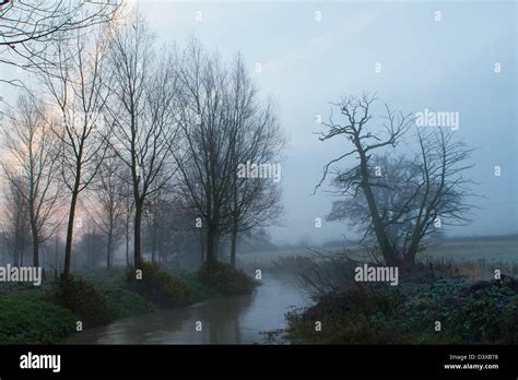 River Running Through Misty Fields On A Cold Winters Morning Stock