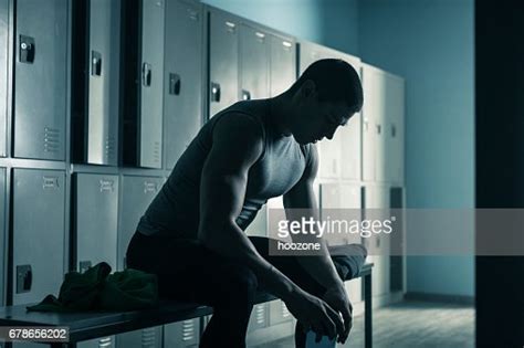 Man Sitting On Bench In Locker Room After Workout In Gym High Res Stock