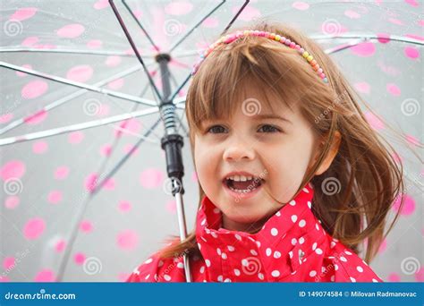 Portrait Of Little Cute Girl In Red Rain Coat Under The Umbrella Stock