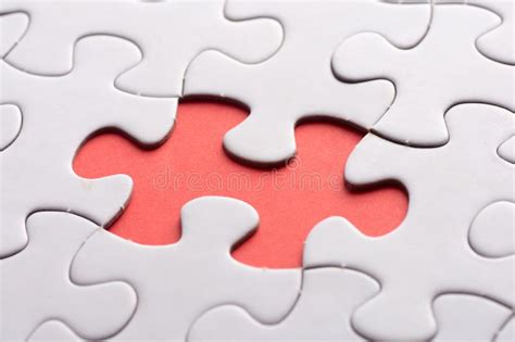 Unfinished White Jigsaw Puzzle Pieces On Red Background Stock Photo