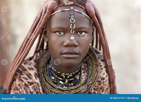 Portrait Of A Himba Girl Looking After The Goat Herd Carrying A Baby On