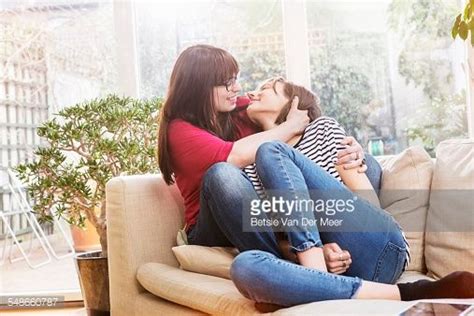 Lesbian Couple Cuddling On Sofa In Livingroom Cuddling Couples Couple Poses Reference