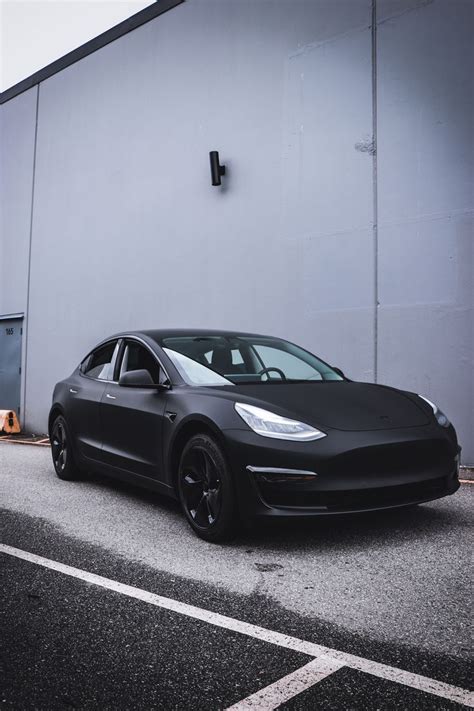 A Black Tesla Parked In Front Of A Building