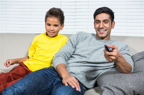 Sonriente Padre Viendo La Televisión Con La Hija En El Sofá Foto Premium