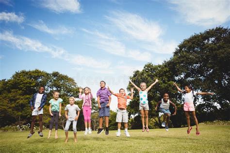 Niños Sonrientes Que Saltan Junto Durante Un Día Soleado Imagen De