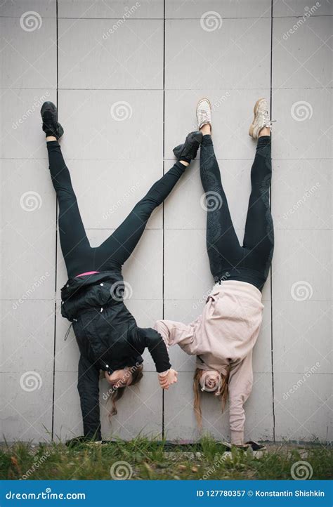 Two Girls Acrobats Holding Hands Performing A Handstand Against The