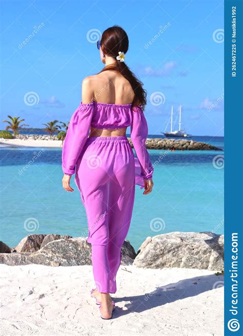 Beautiful Stylish Slender Girl On The Beach In The Maldives Stands With
