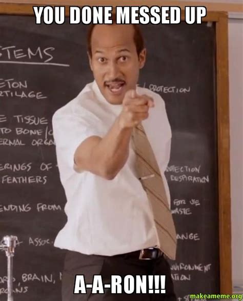 A Man Pointing At The Camera In Front Of A Blackboard