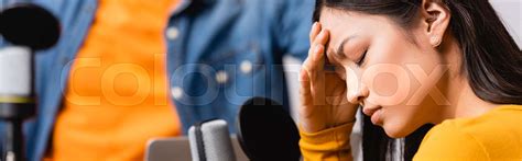 Selective Focus Of Radio Host Near Offended Asian Woman With Closed Eyes Touching Head During