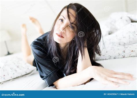 Young Woman With Dark Hairs In Her Face Laying In Bed In Black Dressing