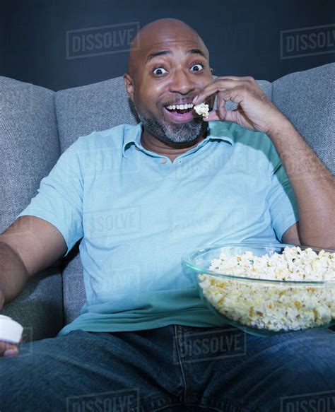 African American Man Eating Popcorn And Watching Television Stock