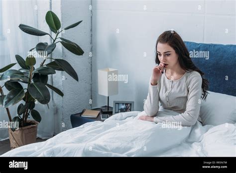 Beautiful Depressed Woman Lying In Bed And Biting Finger Stock Photo