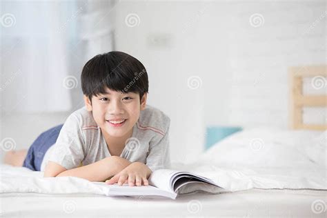Happy Asian Boy Reading Story Book On The Bed Stock Photo Image Of